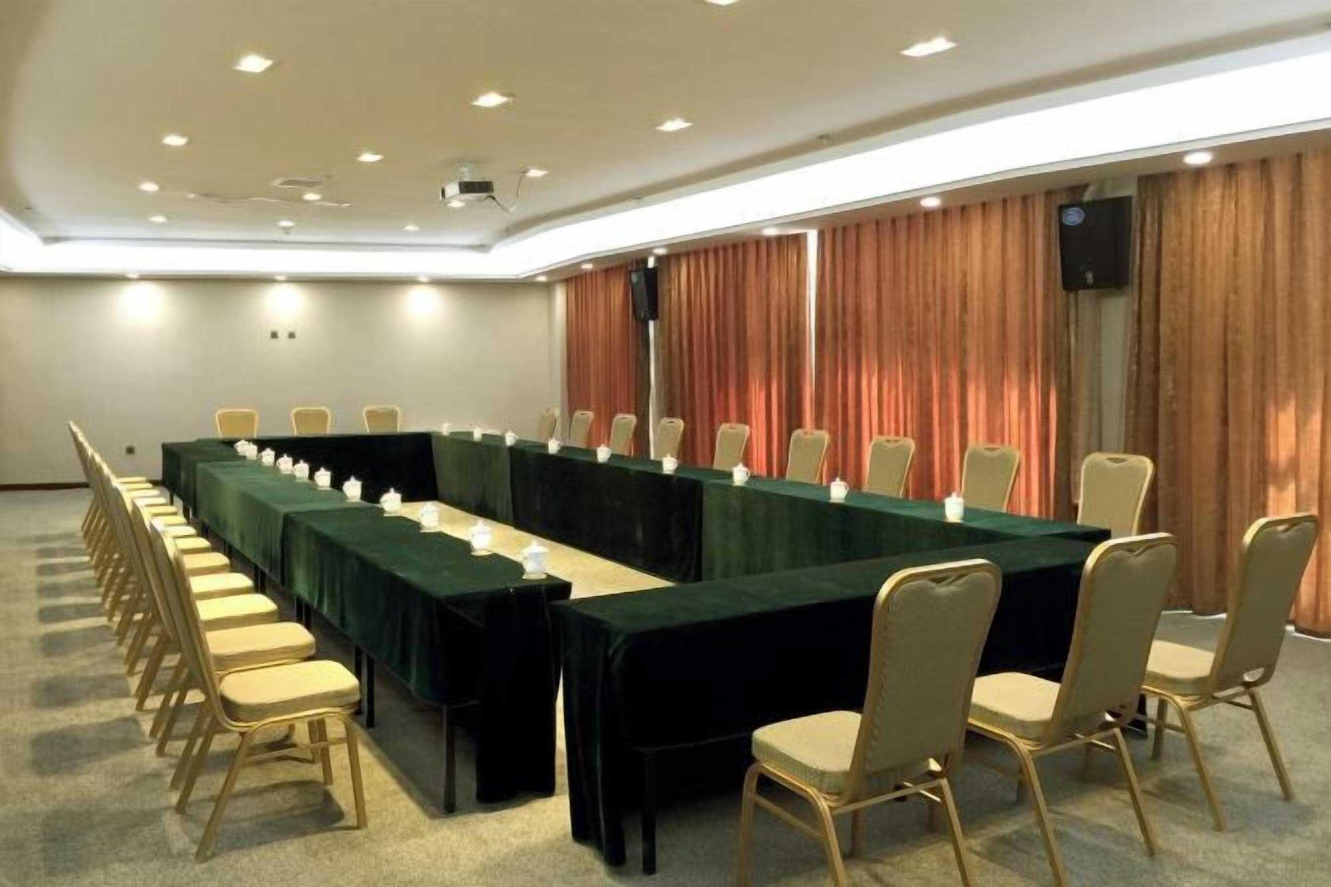 Un salón de conferencias con una larga mesa, sillas y una pantalla para proyector.