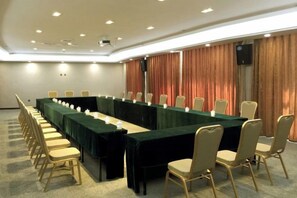 A conference room with a long table, chairs, and a projector screen.