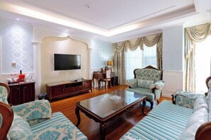 A living room with a sofa set, a coffee table, a TV, and a patterned wall.