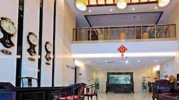 A lobby with a reception desk, seating area, and a large screen displaying a scenic image.