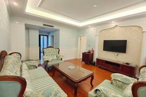 A living room with a sofa set, a coffee table, and a television mounted on the wall. - Manas County Hotel (Manas County)