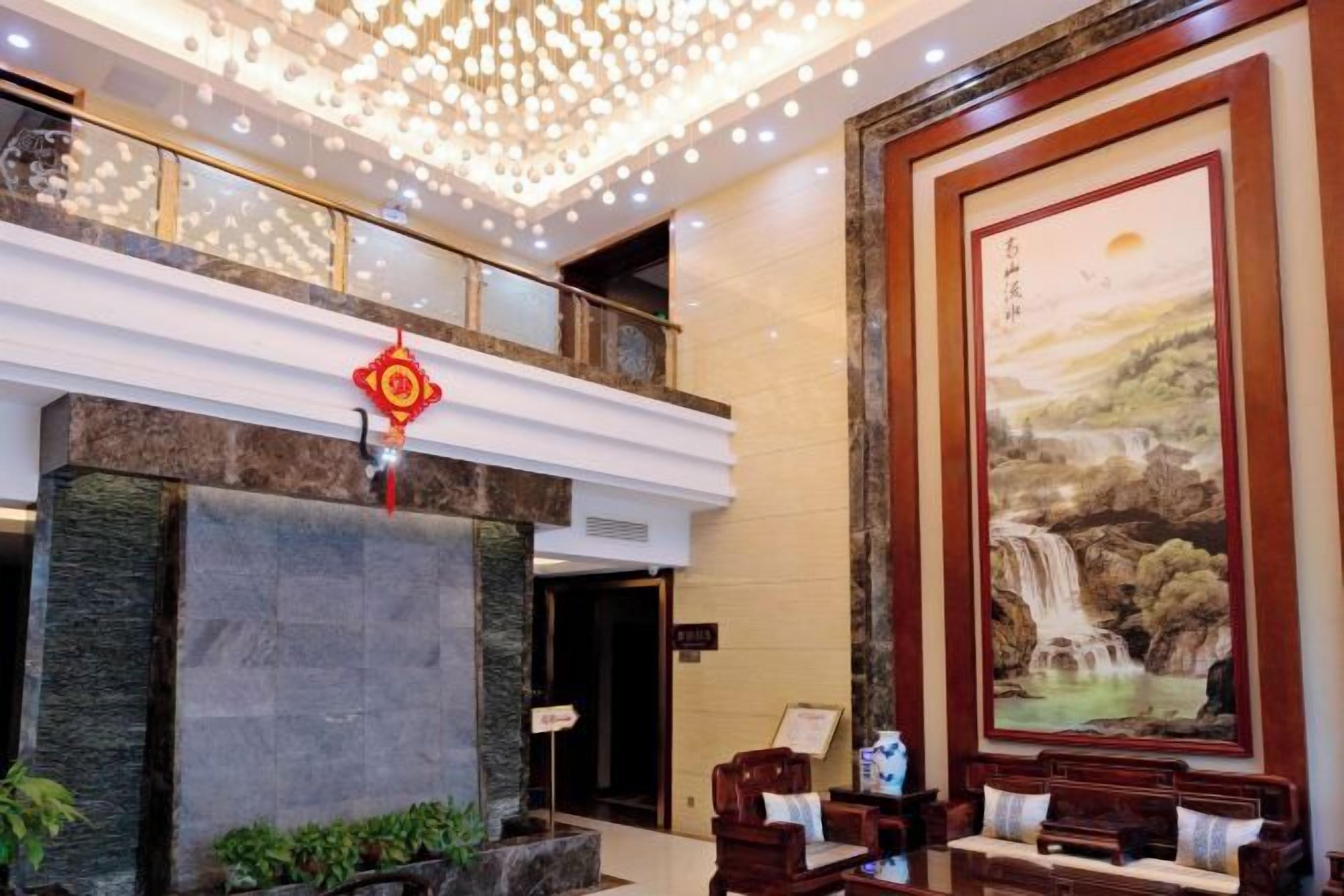 A lobby with a reception desk, a large painting, and a decorative ceiling.