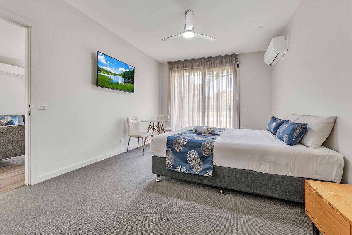 A modern bedroom with a bed, a desk, and a chair.