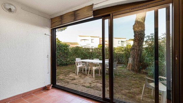 A room with a sliding glass door leading to an outdoor patio area with a table and chairs. - Spacious Apt 7 ppl, terrace, near the sea (Agde)