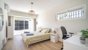 Une chambre à coucher comprenant un lit, une table de chevet, une chaise, un bureau et une fenêtre donnant sur un paysage agréable.