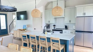 Una cucina moderna con isola centrale, mobili bianchi e frigorifero in acciaio inossidabile.