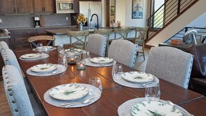 A dining area with a long wooden table set for six, surrounded by upholstered chairs. - New, modern mountain retreat for several families 8 min from ski resort. (Fraser)