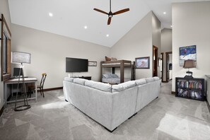 A modern living room with a sofa, a television, a ceiling fan, and a bookshelf. - New, modern mountain retreat for several families 8 min from ski resort. (Fraser)