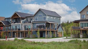 A multi-story residential building with a prominent balcony, a covered front porch, and a stone facade. - New, modern mountain retreat for several families 8 min from ski resort. (Fraser)