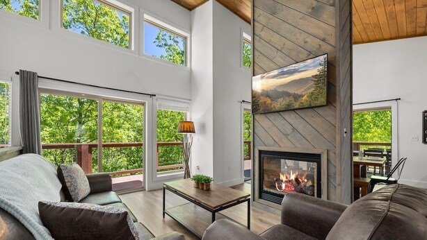 A spacious living room with a fireplace, large windows, and a cozy seating area. - Modern, Cozy with Stunning Mountain View, Hot Tub, Arcade, Mins to the Smokies (Seiverville)