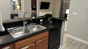 A modern kitchen with a double sink, a coffee maker, and a dishwasher. - Close to Disney and Universal! Family-sized condo with pool, balcony & game room (Orlando)