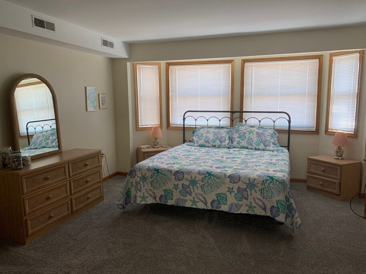 A bedroom with a bed, dresser, nightstands, and a large mirror.