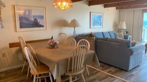 A dining area with a table set for six, surrounded by wooden chairs. A chandelier hangs above the table. - Extra large direct oceanfront townhouse. Sleeps 14. (Ocean City)