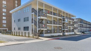 A multi-story apartment building with balconies, a parking lot, and a clear sky. - Ocean view from the balcony of this 3 bedroom condo on 85th Street. (Ocean City)