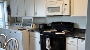 A compact kitchen with white cabinets, a microwave, a stove, and a dishwasher. - Ocean view from the balcony of this 3 bedroom condo on 85th Street. (Ocean City)