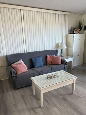 Un salon comprenant un canapé, une table basse, une lampe et un meuble.