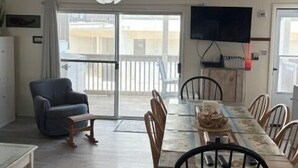 A dining area with a table, chairs, a ceiling fan, and a TV mounted on the wall. - Ocean view from the balcony of this 3 bedroom condo on 85th Street. (Ocean City)