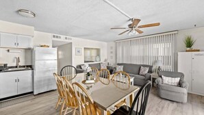 Eine moderne Küche mit Essbereich, Deckenventilator und einem Wohnzimmer mit Sofa und Couchtisch.