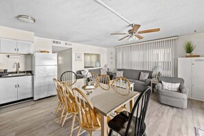 Una cocina moderna con comedor, ventilador de techo y sala de estar con sofá y mesa de centro.