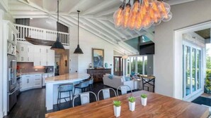 Une cuisine moderne avec des meubles blancs, un îlot central en bois et des luminaires suspendus.