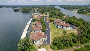 A lakeside residential area with buildings, a dock, and a road leading to a parking lot. - Orchid On The Water - w/ Boat Slip On Lake Hamilton! (Hot Springs)