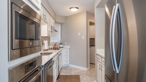 A modern kitchen with stainless steel appliances, white cabinetry, and a marble floor. - Orchid On The Water - w/ Boat Slip On Lake Hamilton! (Hot Springs)