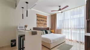 A modern bedroom with a bed, a desk, and a ceiling fan.