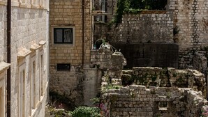 Ein historisches Steinhaus mit Ziegeldach, kleinen Fenstern und einem Innenhof mit Ruinen.