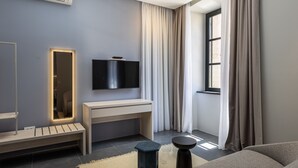 Ein modernes Wohnzimmer mit einem großen Flachbildfernseher an der Wand, einer Holzbank, einem kleinen Beistelltisch und einem Sofa.
