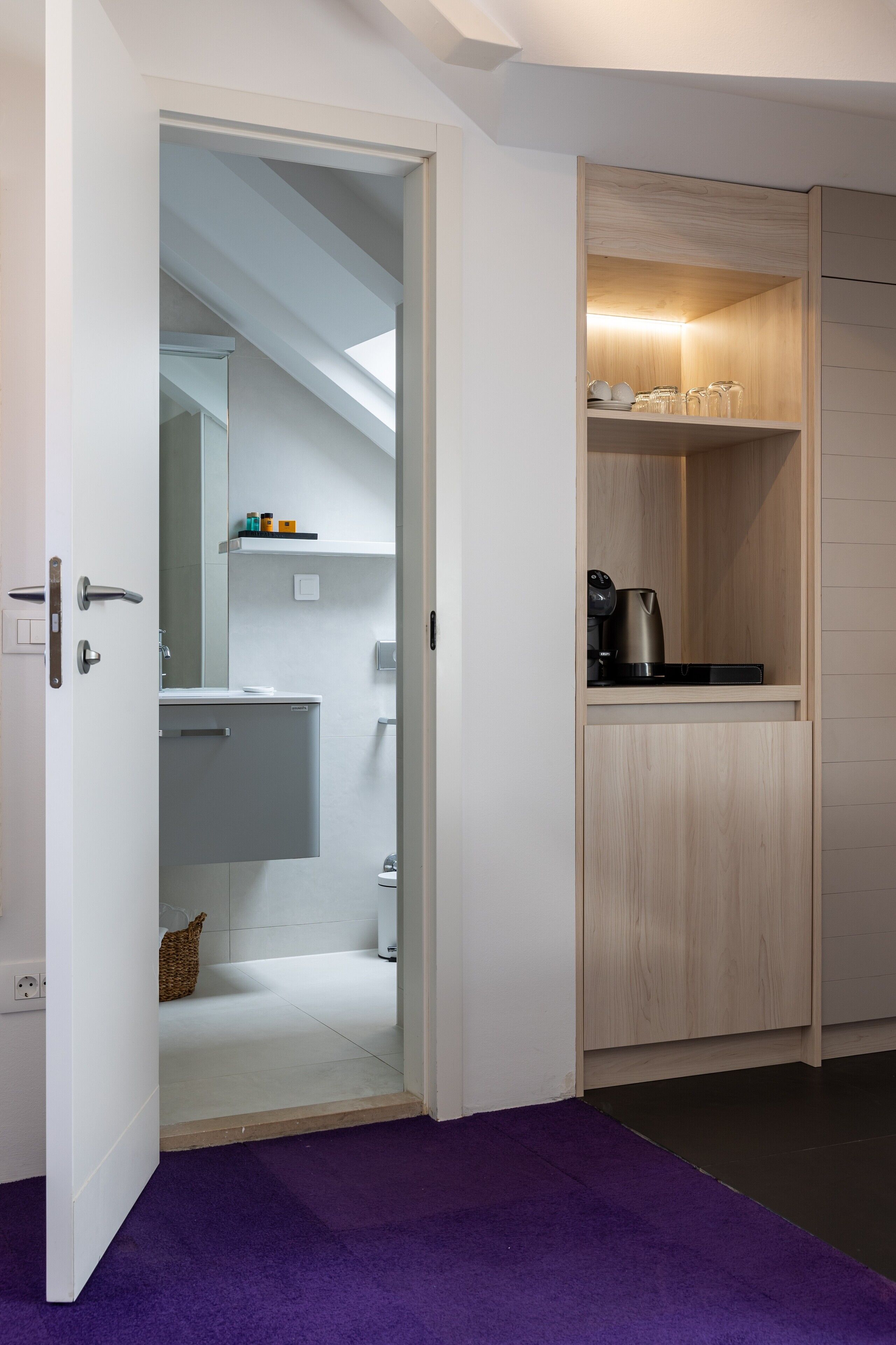 A modern bathroom with a white sink, mirror, and towel rack. A small wicker basket is visible on the floor.