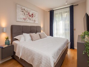 Relax in this serene bedroom featuring a large bed, contemporary headboard, and a flat-screen TV.