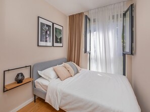 A bedroom with a bed, a nightstand, a window with curtains, and two framed pictures on the wall. - Apartment Floramye - Three Bedroom Apartment with Balcony (Dubrovnik)
