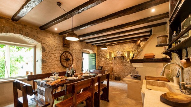 A rustic dining area with wooden benches and a stone wall backdrop. - Authentic Stone House Lola (Makarska)