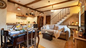 A cozy living room with a wooden dining table set for breakfast, a sofa with cushions, and a staircase leading to an upper level. - Authentic Stone House Lola (Makarska)