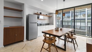 Une cuisine moderne dotée d’un réfrigérateur encastré, de meubles en bois et d’une grande fenêtre offrant une vue sur la ville.