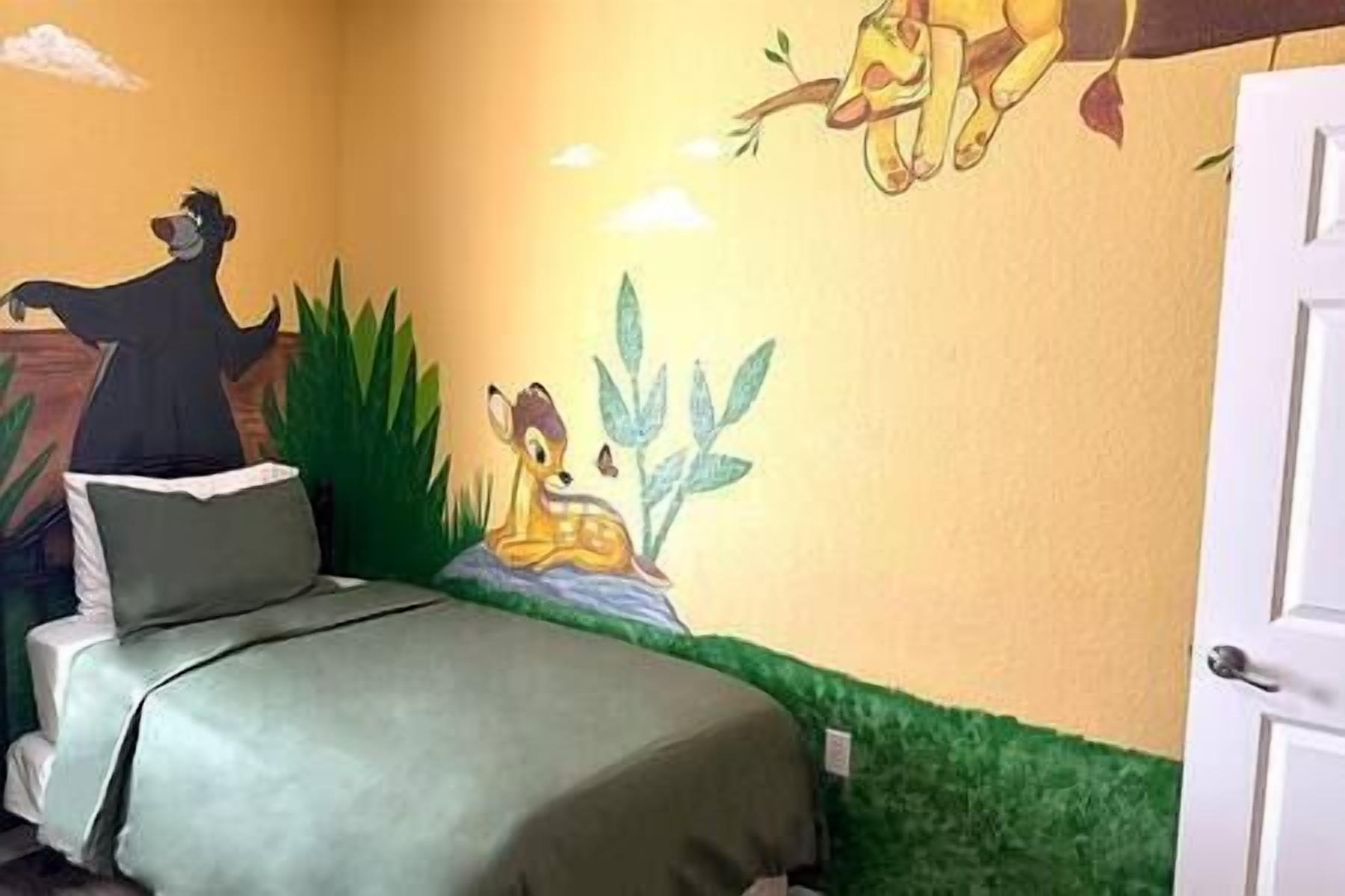 A bedroom with a bed, a wall mural, and a door.