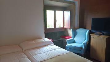 A room with two beds, a TV, and a chair.