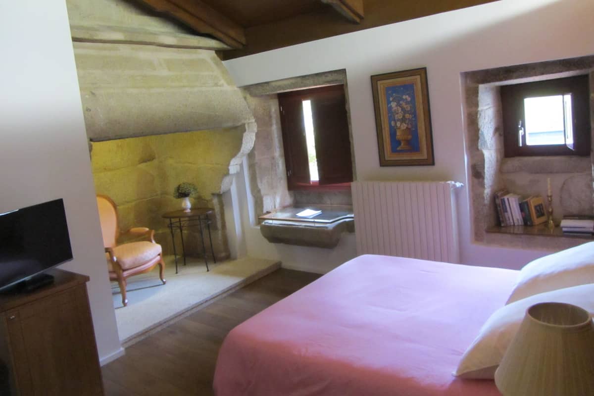 A bedroom with a bed, a chair, a small table, and a television.