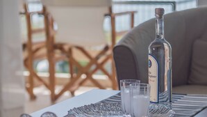 A table with a bottle and glasses on a tray, overlooking a balcony with chairs. - Seafront Apartment Grace (Kalamata)