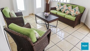 Una sala de estar con muebles de mimbre, un sofá verde y una mesita de centro.