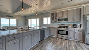A modern kitchen with grey cabinetry, stainless steel appliances, and a wooden floor.