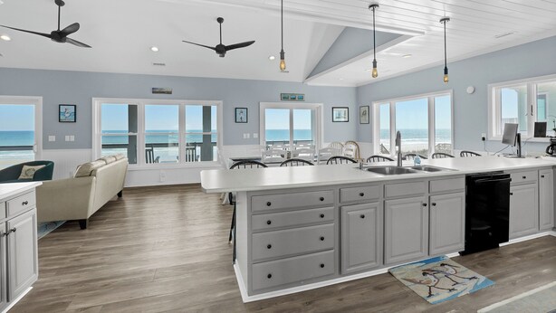 A modern kitchen with a large island, white cabinetry, and a view of the ocean.