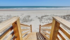 A wooden staircase leading to a beach with a clear view of the ocean.