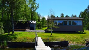 A lakeside property with a dock leading to a house and a smaller cabin.