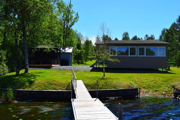 A lakeside property with a dock leading to a house and a smaller cabin.