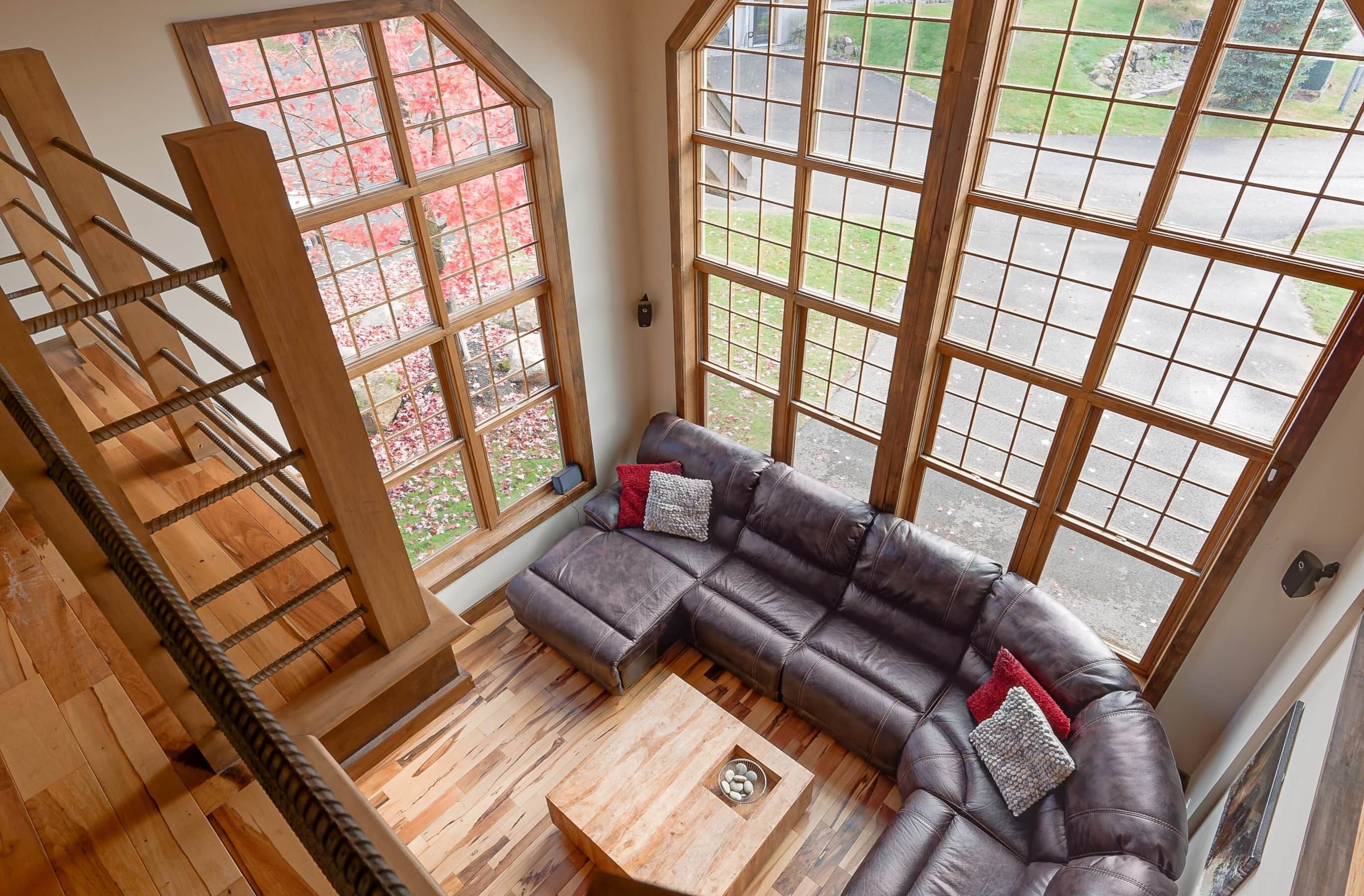 Ein modernes Wohnzimmer mit einer Holztreppe, großen Fenstern und einem Ecksofa.