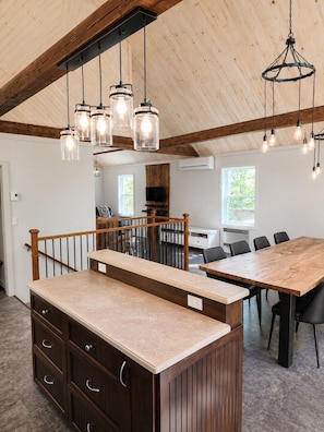 Cocina moderna con detalles de madera, una isla central e iluminación colgante.