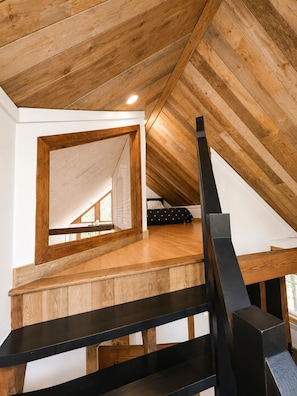 Un dormitorio en el ático con vigas de madera, techo inclinado y un espejo grande.