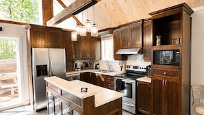 Une cuisine moderne avec des meubles en bois, des appareils électroménagers en acier inoxydable et un grand îlot central.