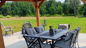 Un patio exterior con una pérgola de madera, una mesa y seis sillas.
